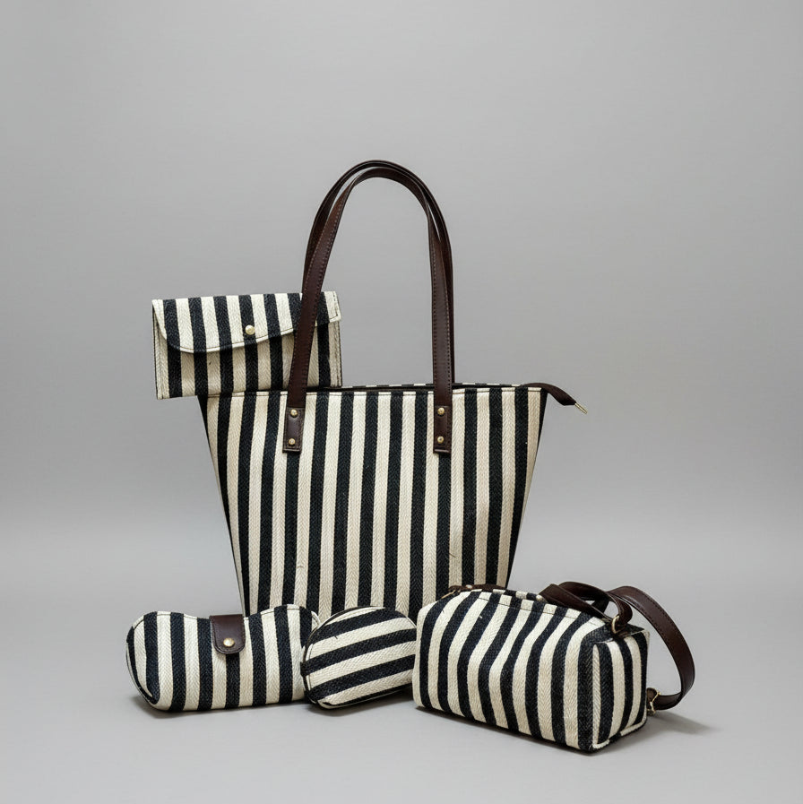 Set of black and white striped bags with brown handles against a textured wall.